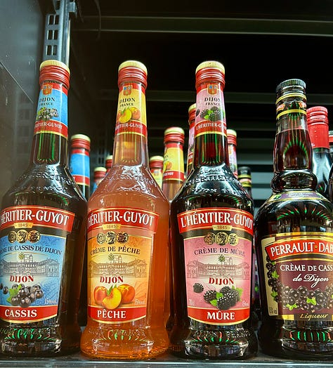 French wines and fruit syrups for making a kir cocktail, along with bottles and glasses