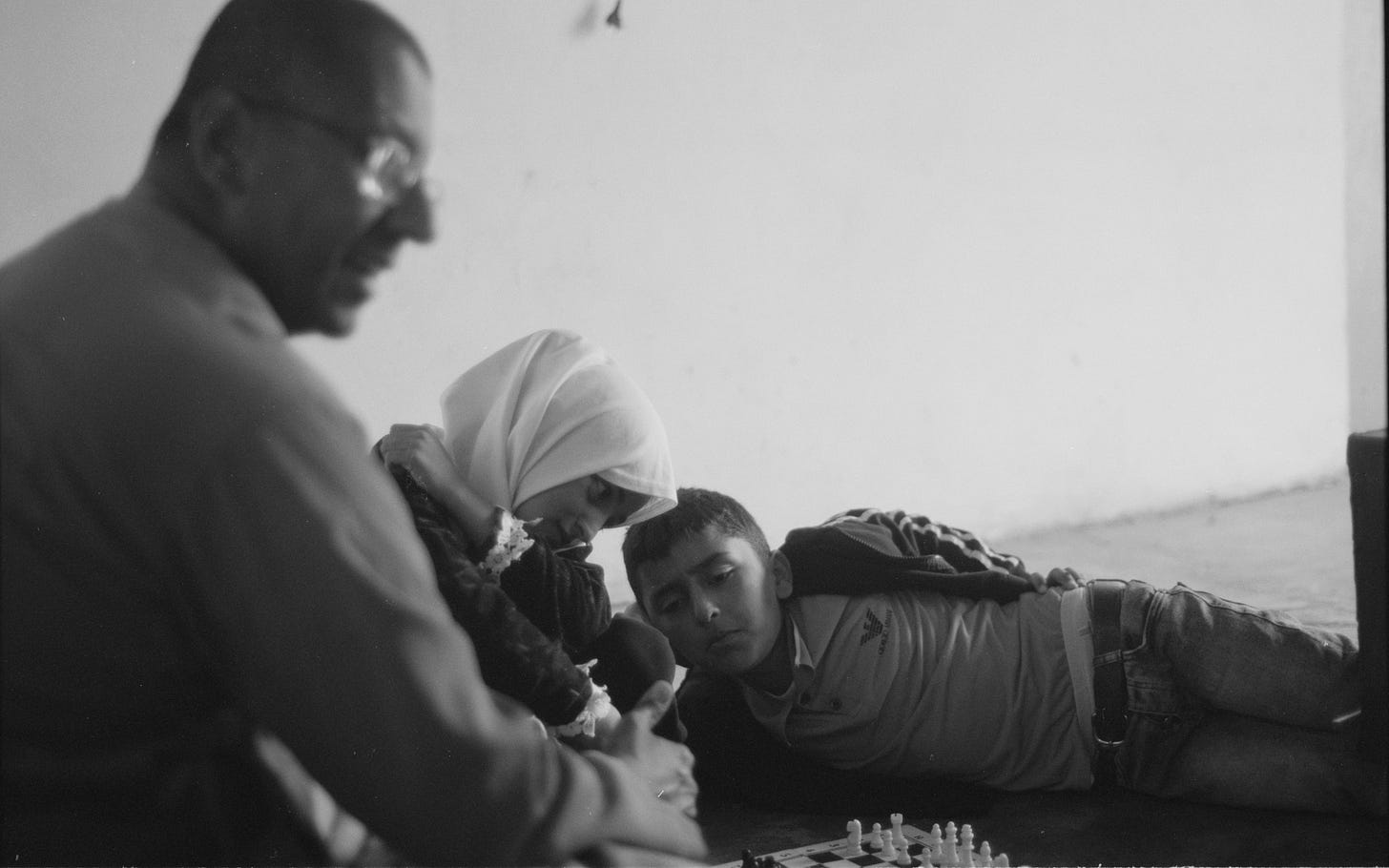 A black and white photo of a Buddhist monk and two Palestinian children playing chess.