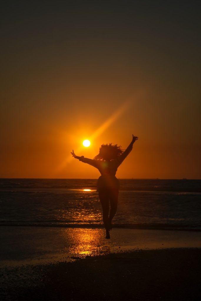 silhouette of woman standing on beach during sunset silhouette of woman standing on beach during sunset