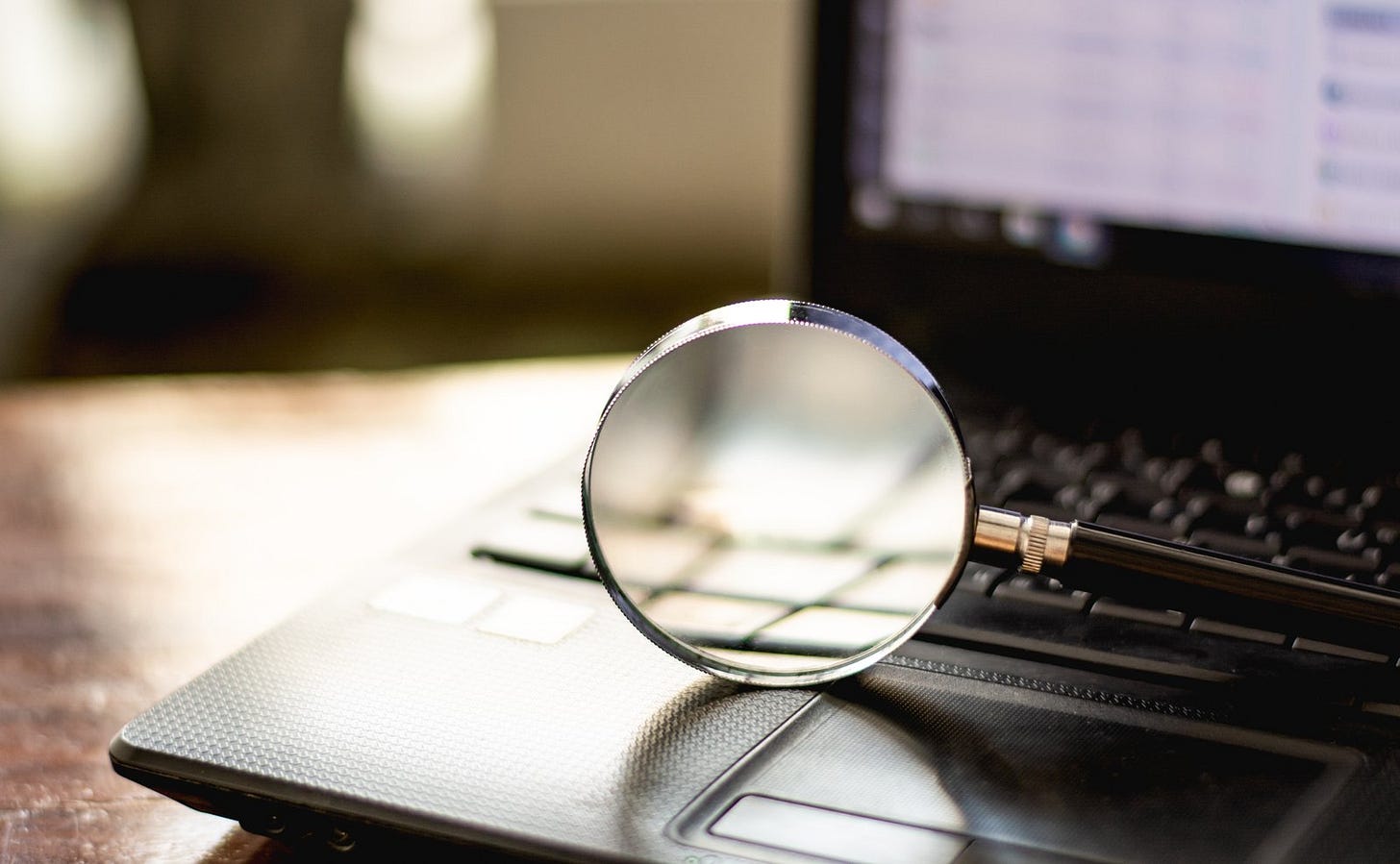 A magnifying glass on a laptop keyboard A magnifying glass on a laptop keyboard