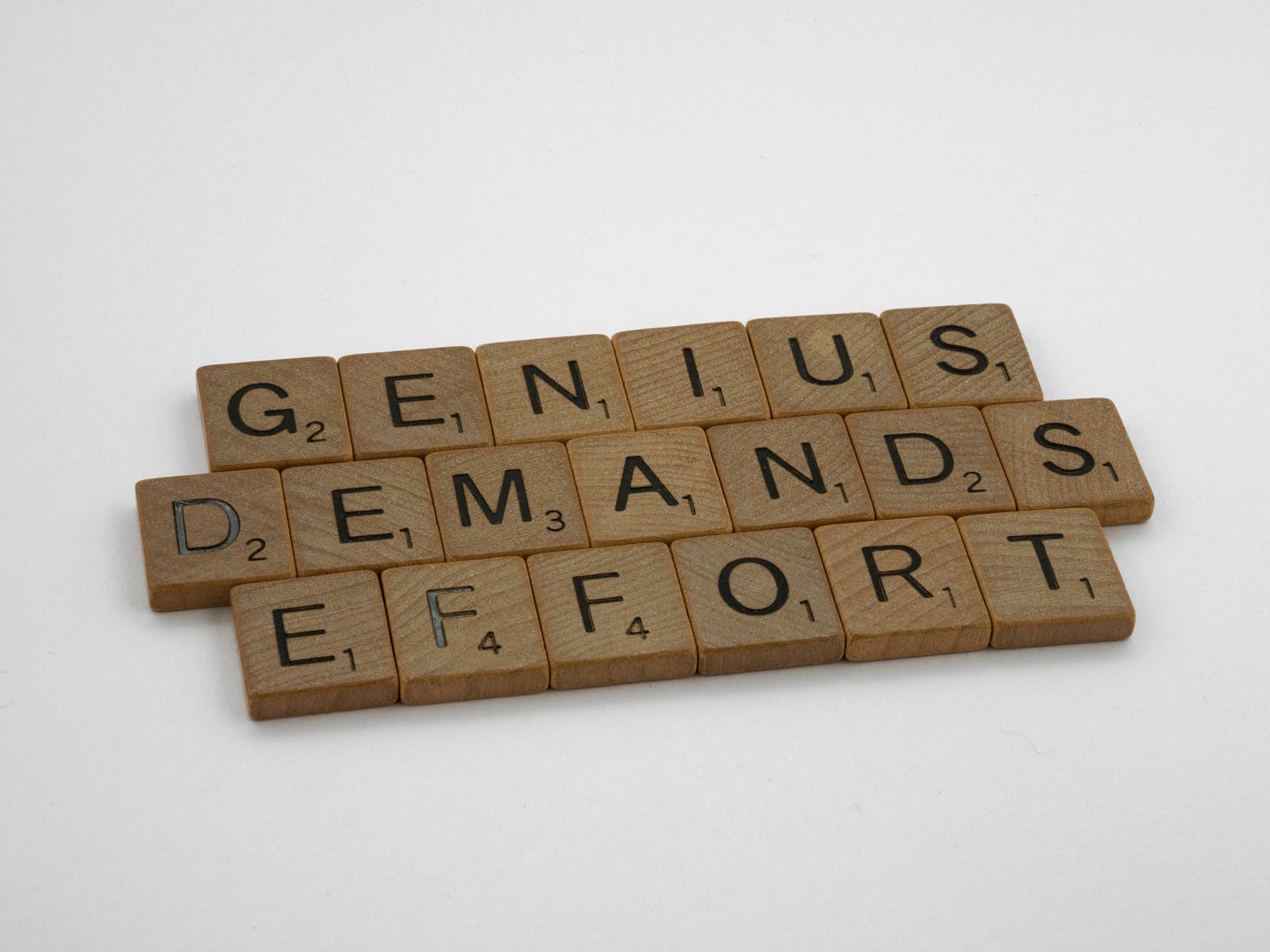 scrabble blocks that read "genius demands effort"