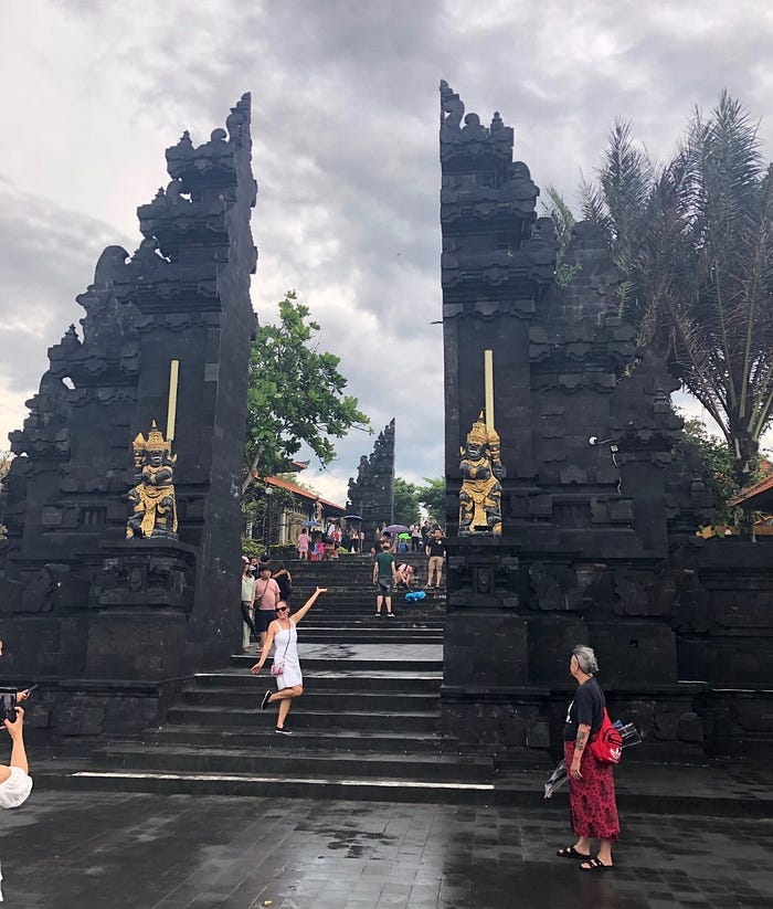 Large black entrance gate in Bali with people taking photos.