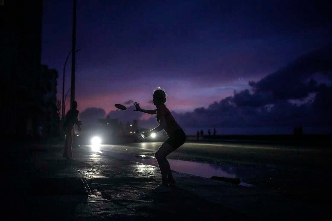 A woman prepares to catch a tossed frisbee during a massive blackout after a major power plant failed in Havana, Cuba, Friday, Oct. 18, 2024.