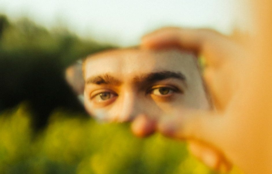 Man's eyes reflected in a handheld mirror outdoors