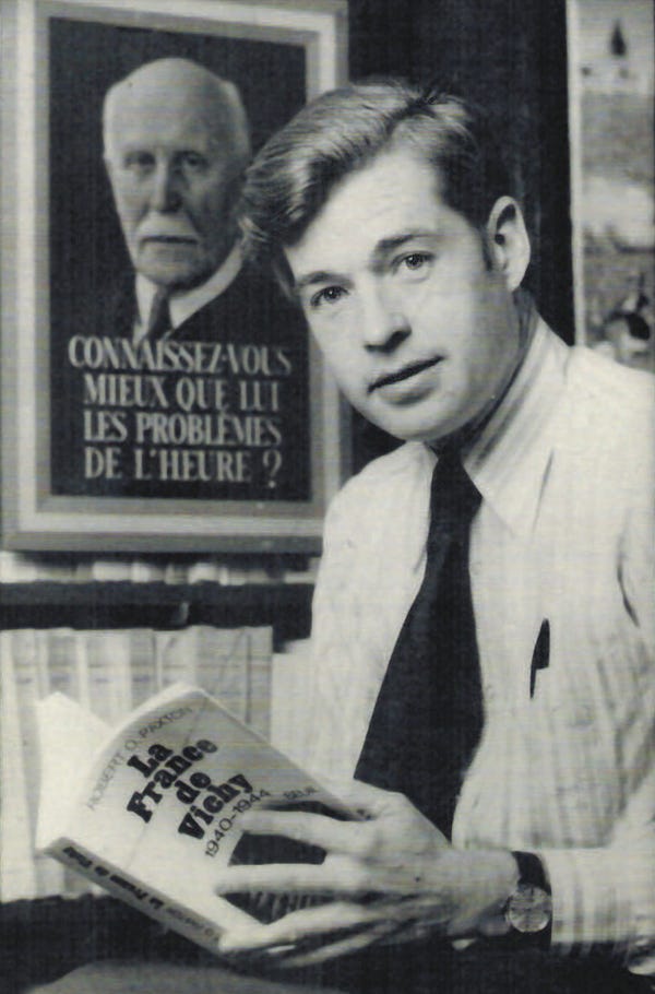 A black-and-white photograph of Paxton with his book “Vichy France.”
