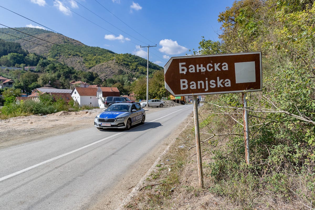 A traffic safety police vehicle drives past a damaged destination sign that says "Banjska" in the village of Banjska, Zvecan, Kosovo, on Oct. 3, 2023. (Photograph by Vudi Xhymshiti for THE PICTURES, via VX Pictures)