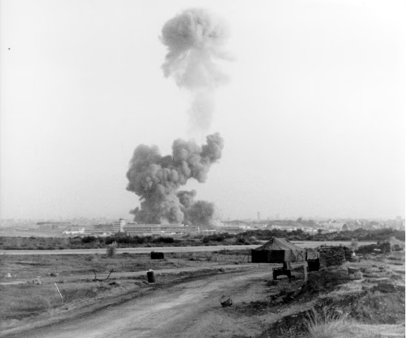 Black-and-white photo showing a massive plume of smoke rising from the site of the U.S. Marine Barracks in Beirut, Lebanon, moments after the truck bomb detonation on October 23, 1983.