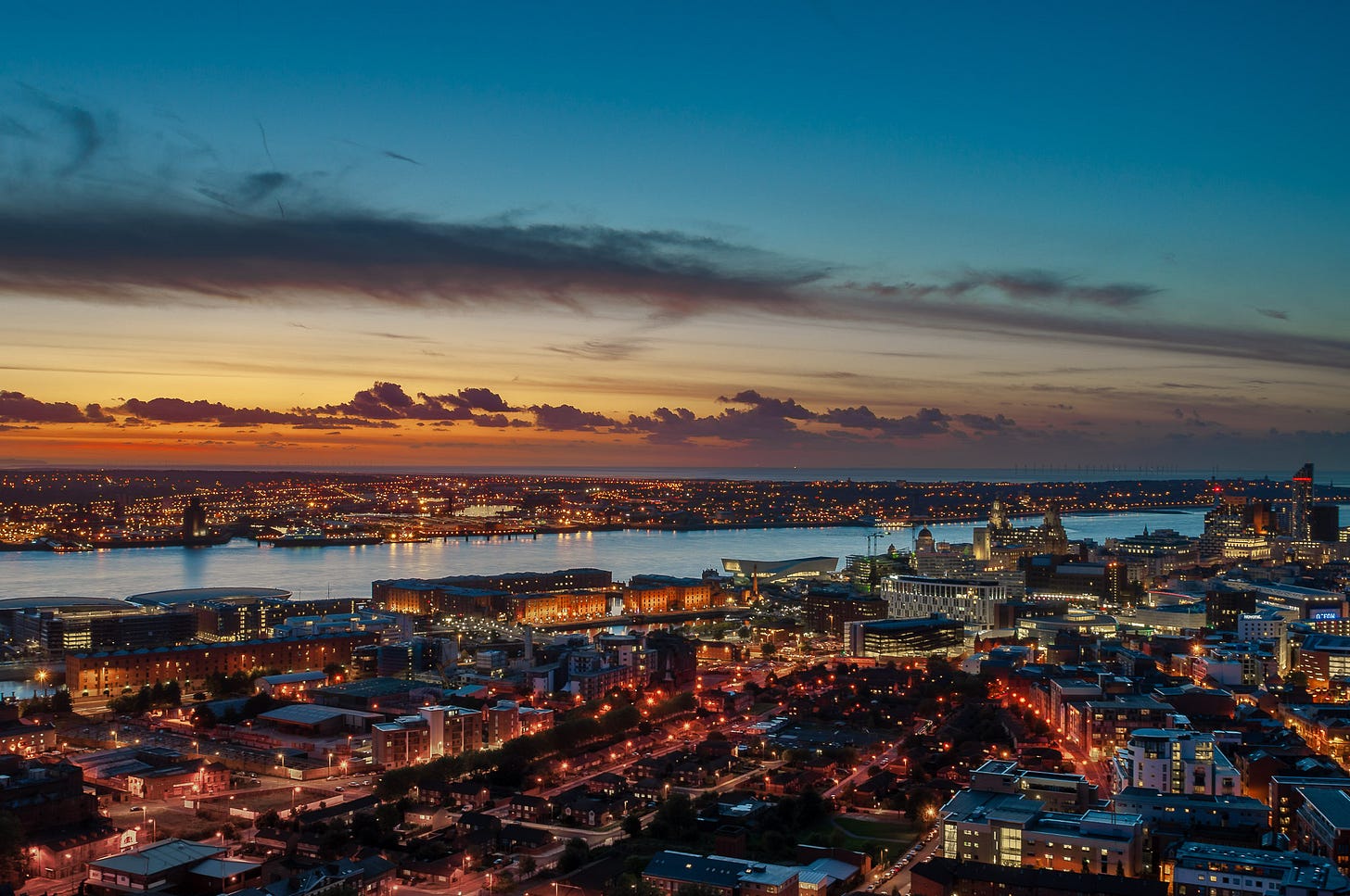 Dusk. The lights of the city are on. This is the Liverpool waterfront from the arena to Beetham Tower including the Royal Albert Dock, Museum of Liverpool and the 3 Graces.