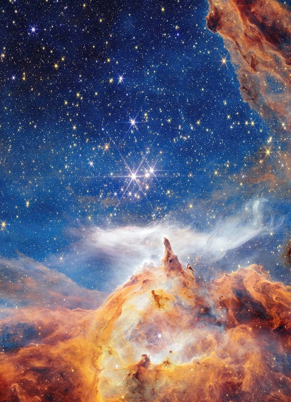 In what appears as a celestial dreamscape, a blue and black sky filled with brilliant stars covers about two thirds of the image. The stars are different sizes and shades of white, beige, yellow, and light orange. Across the bottom third of the scene is a craggy, mountain-like vista with spire-like peaks and deep, seemingly misty valleys. These so-called mountains appear in varying shades of orange, yellow, and brown. Above their soaring spires is a wispy, ethereal white cloud that stretched horizontally across the scene. Steam appears to rise from the mountaintops and join with this cloud. At the top, right corner of the image, a swath of orange and brown structure cuts diagonally across the sky. In what appears as a celestial dreamscape, a blue and black sky filled with brilliant stars covers about two thirds of the image. The stars are different sizes and shades of white, beige, yellow, and light orange. Across the bottom third of the scene is a craggy, mountain-like vista with spire-like peaks and deep, seemingly misty valleys. These so-called mountains appear in varying shades of orange, yellow, and brown. Above their soaring spires is a wispy, ethereal white cloud that stretched horizontally across the scene. Steam appears to rise from the mountaintops and join with this cloud. At the top, right corner of the image, a swath of orange and brown structure cuts diagonally across the sky.