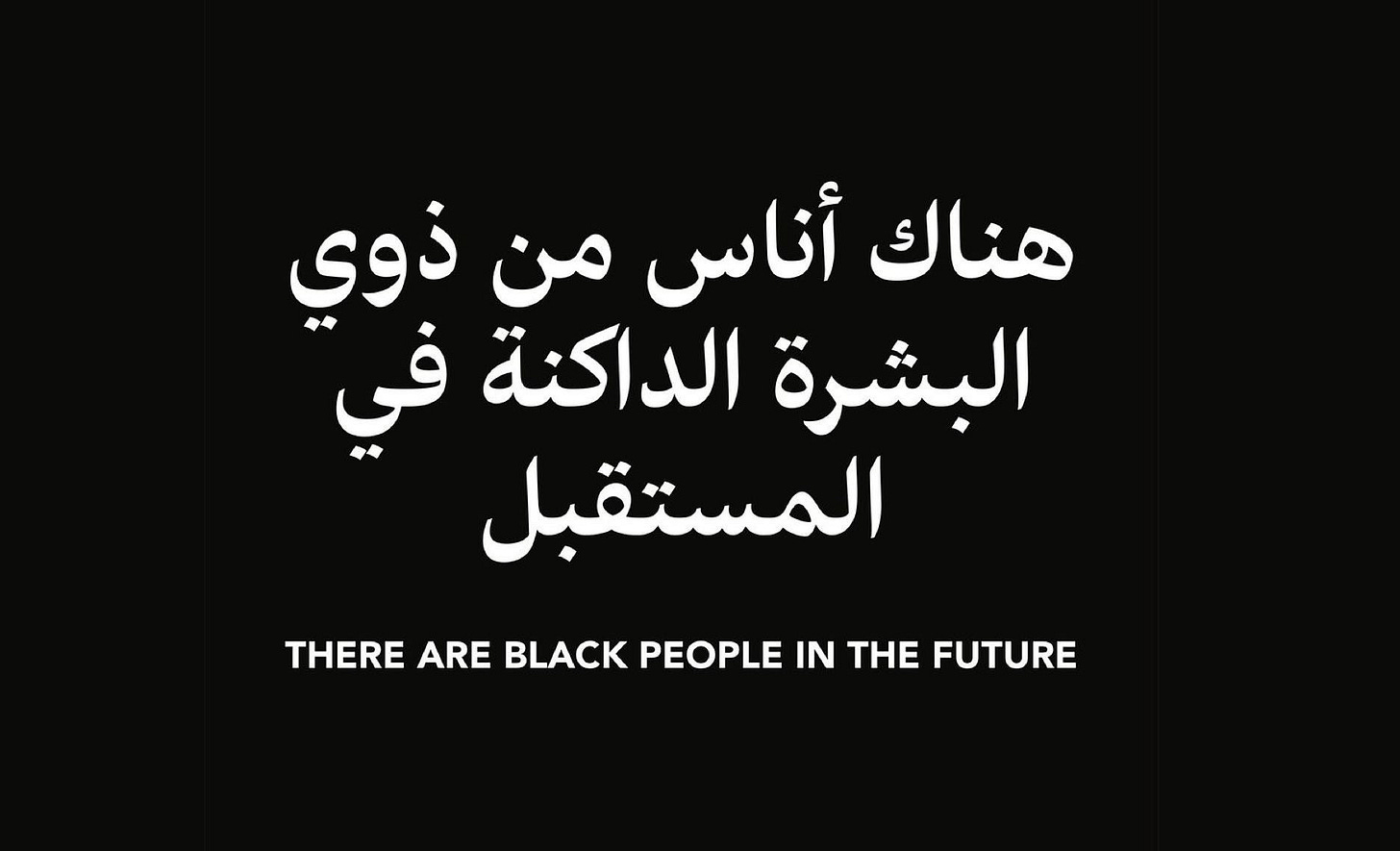 White text on black saying "THERE ARE BLACK PEOPLE IN THE FUTURE" in English and Arabic. The original art piece was by the artist Alisha B. Wormsley.