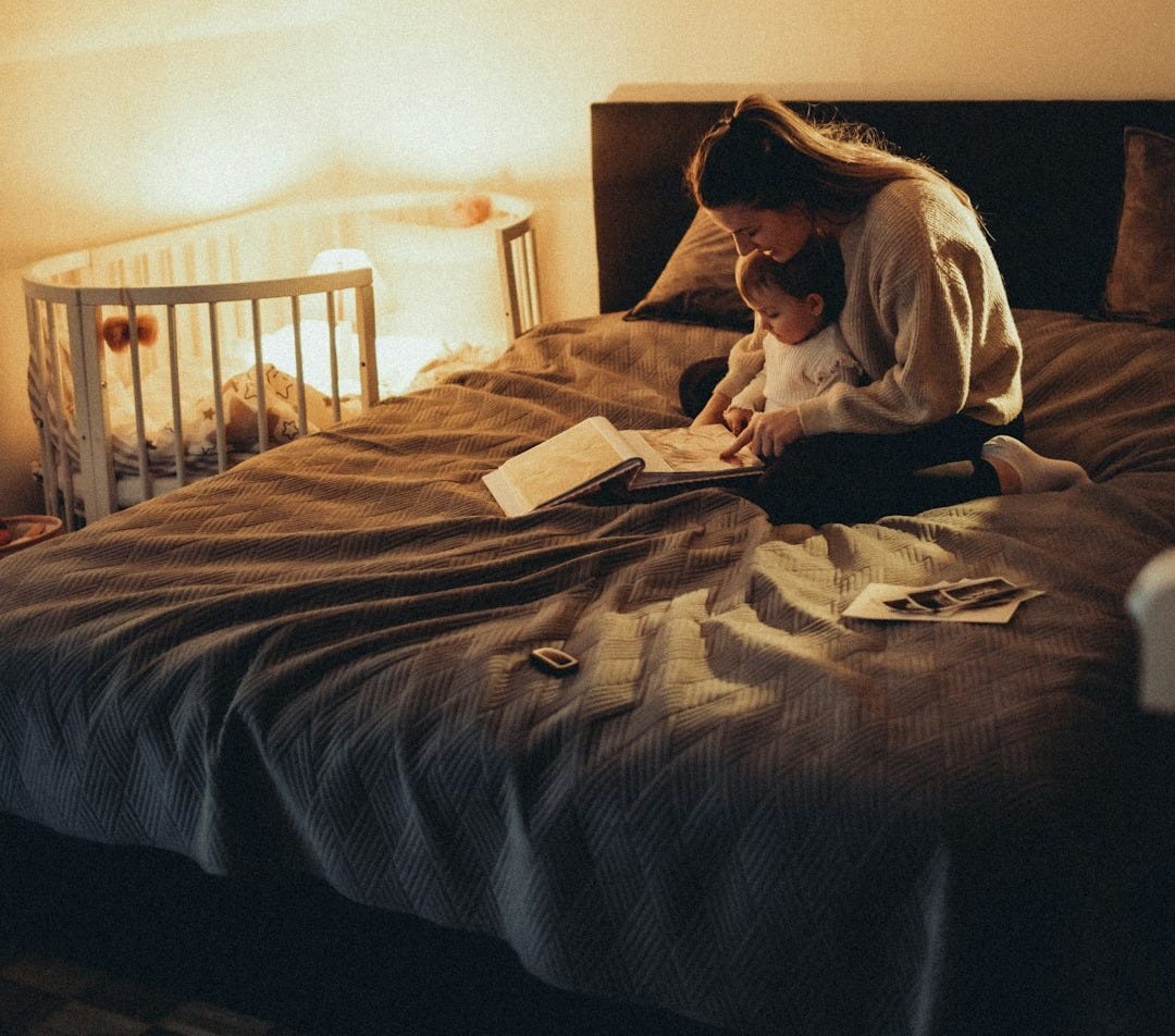 a woman sitting on a bed reading a book