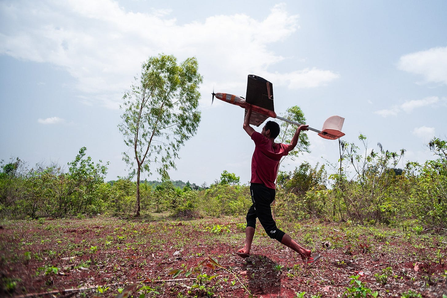 Person running in a forest while holding a drone
