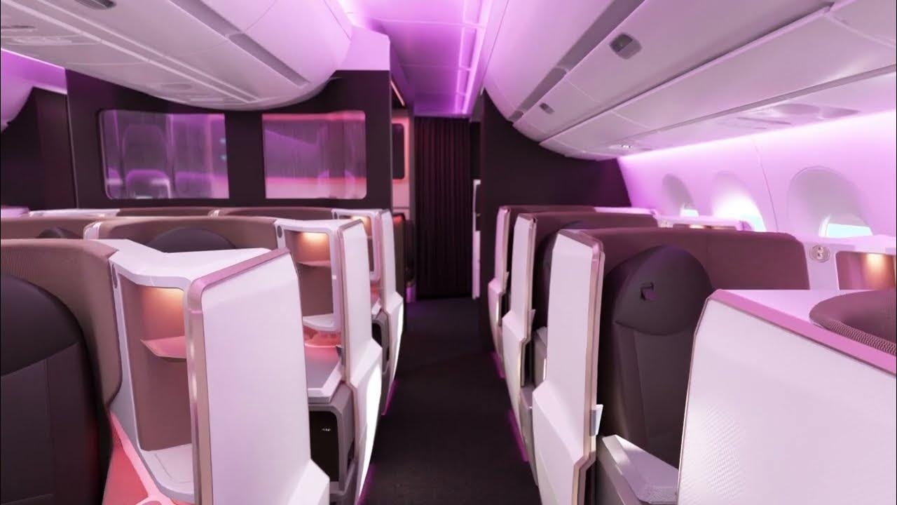 Virgin Atlantic A350 Upper Class business class cabin with private suite-style seats, white seat shells, burgundy upholstery, overhead bins, window-side seats, and purple mood lighting.