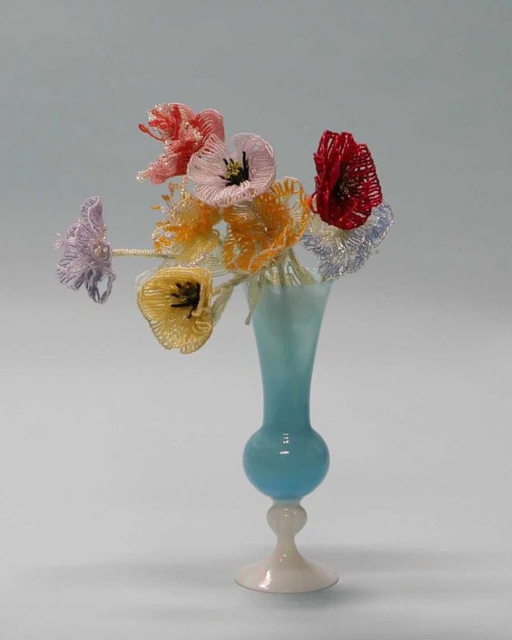 This may contain: a blue vase filled with colorful flowers on top of a table