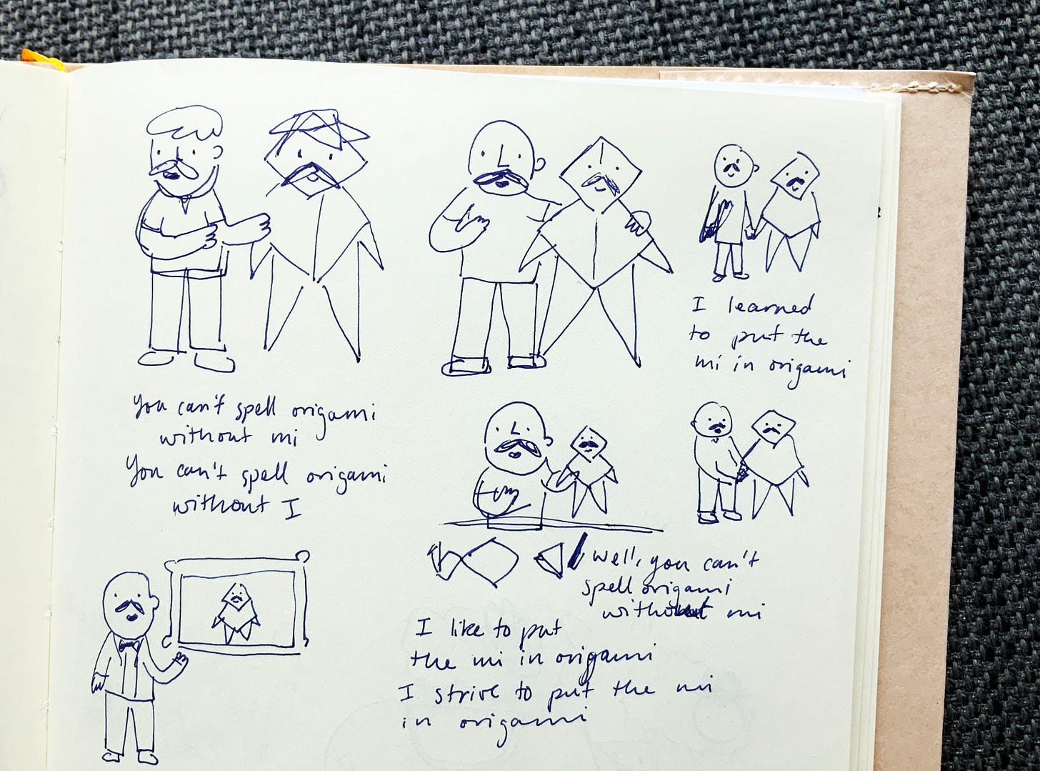 Photo of a sketchbook with multiple drawings of a man with a moustache holding a man made of origami. The origami man has a face and moustache drawn on and is sometimes life-sized.