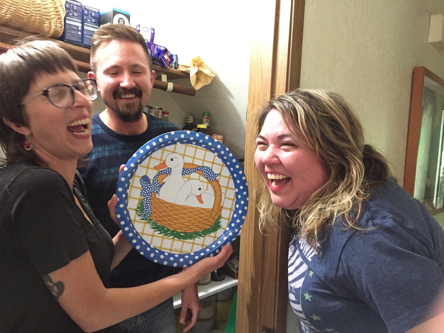 three people laughing at a serving tray printed with geese