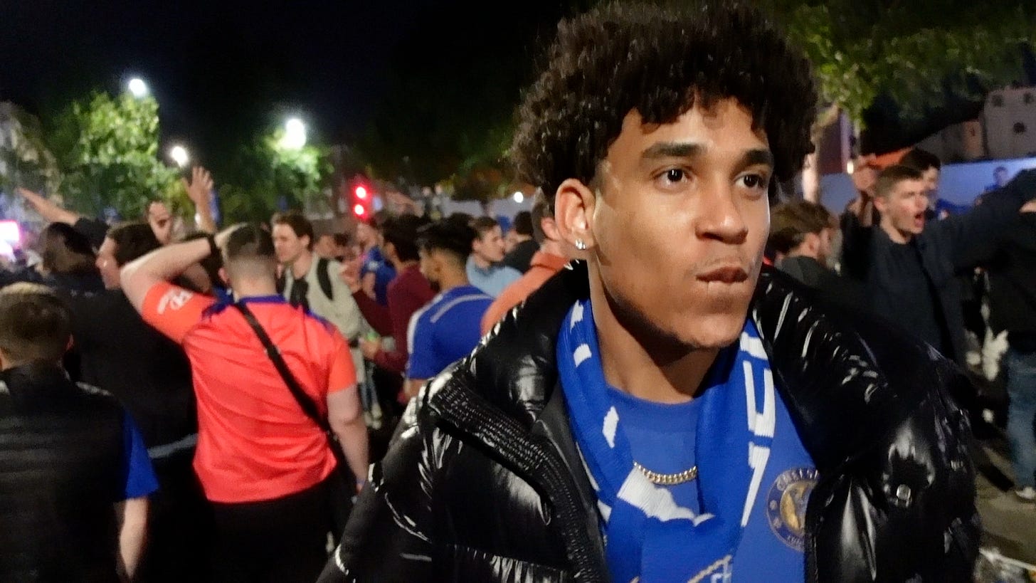 Joshua Arthur in a Chelsea scarf and black puffer jacket among a crowd at night in London, 30 May 2021. Joshua Arthur in a Chelsea scarf and black puffer jacket among a crowd at night in London, 30 May 2021.