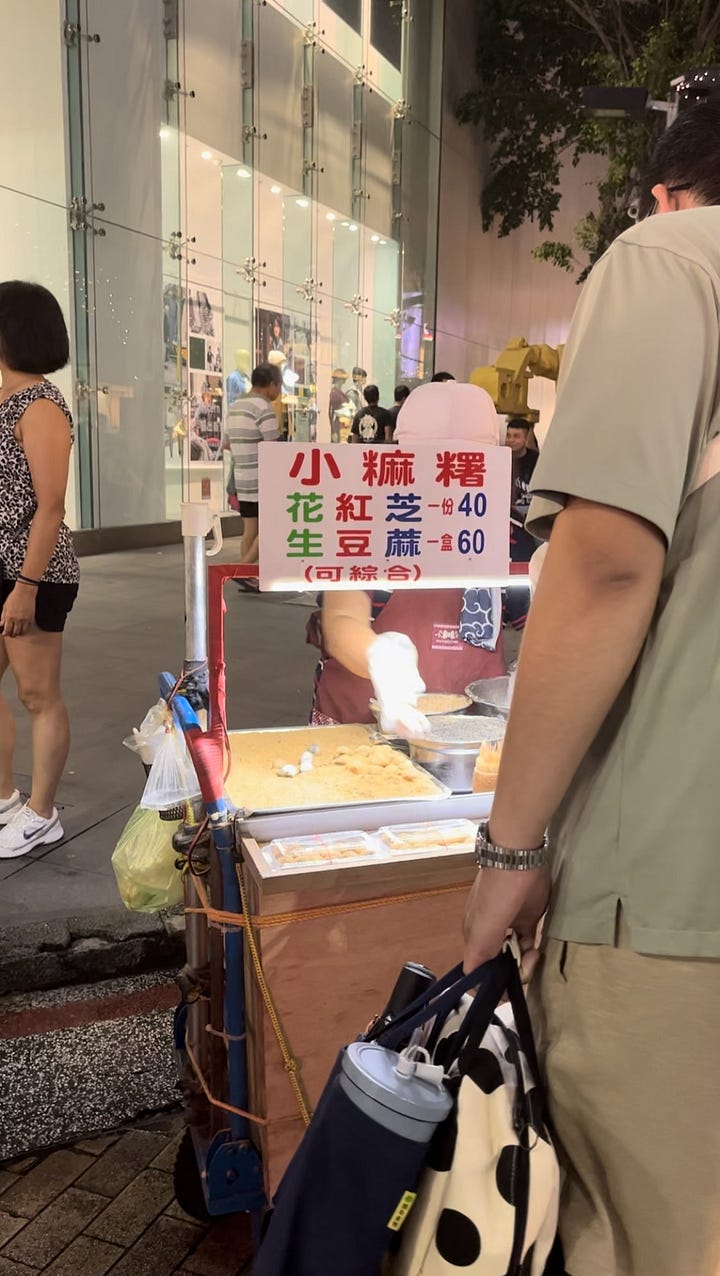 on the left, street stall selling meat skewers. on the right, street stall selling chinese rice cakes