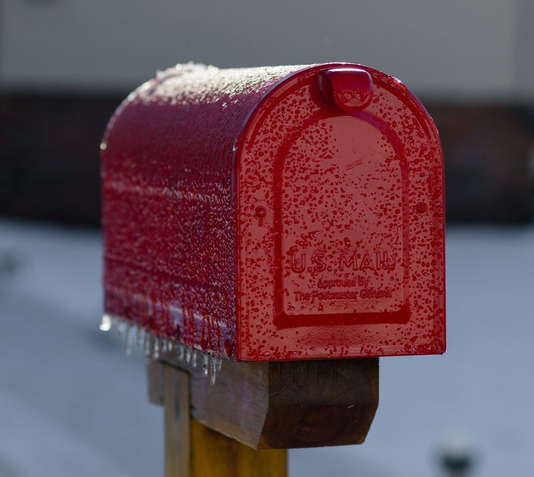a red mailbox sitting on top of a wooden post