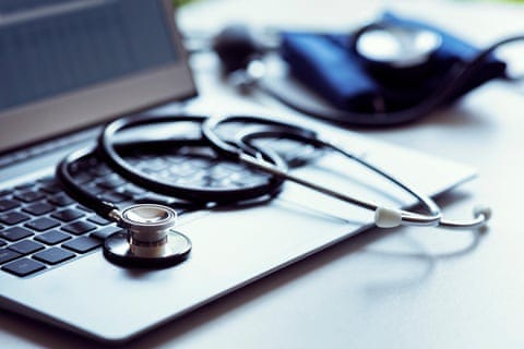Stethoscope on laptop keyboard in doctor surgery with blood pressure monitor Stethoscope on laptop keyboard in doctor surgery with blood pressure monitor