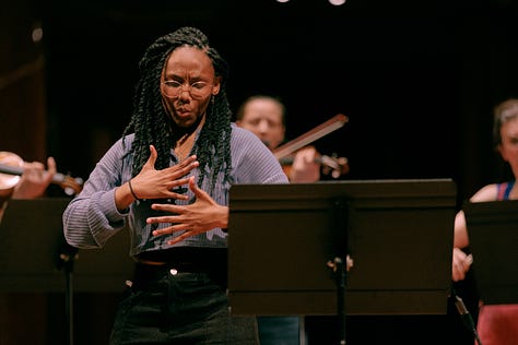 Actress Vilma Jackson, using sign language, standing in the middle of the stage, surrounded by United Strings of Europe musicians