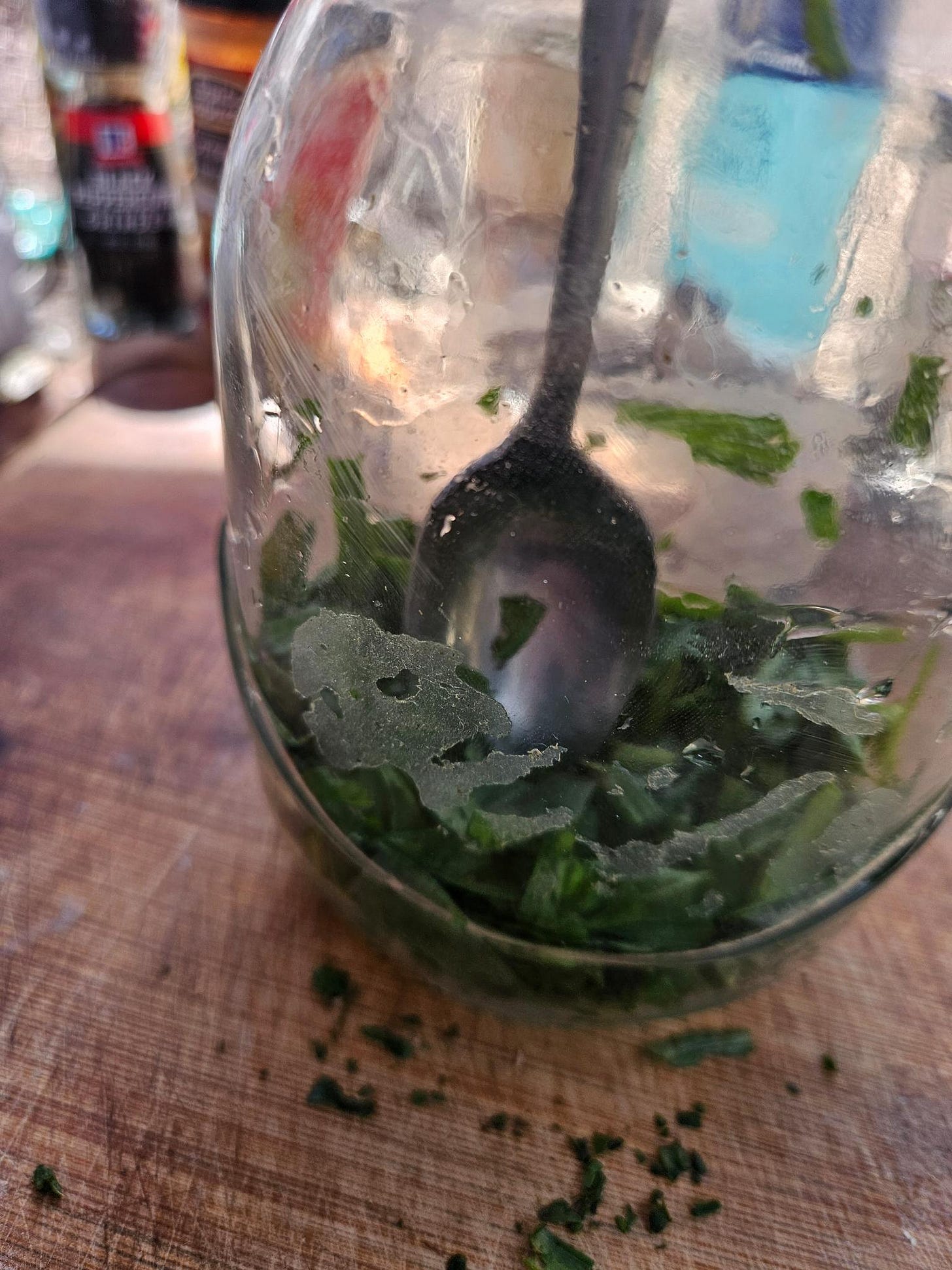 Plantain in a jar with a spoon pressing the leaf pieces down.