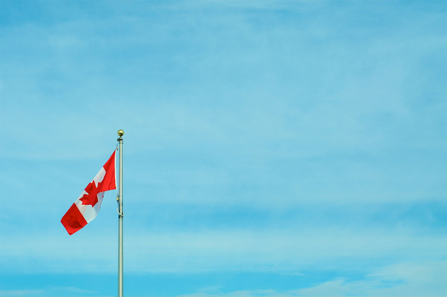 Foto em cores de bandeira do Canadá sob céu azul. Foto em cores de bandeira do Canadá sob céu azul.