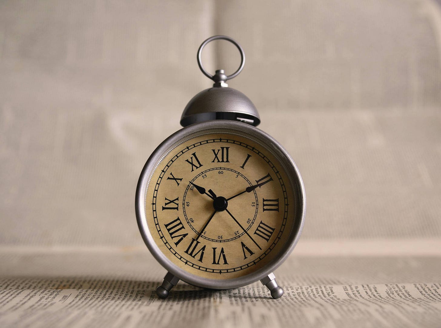  A vintage alarm clock with Roman numerals, placed on a newspaper—symbolizing the role of consistent sleep schedules and time-based interventions in optimizing health. order of operations for longevity