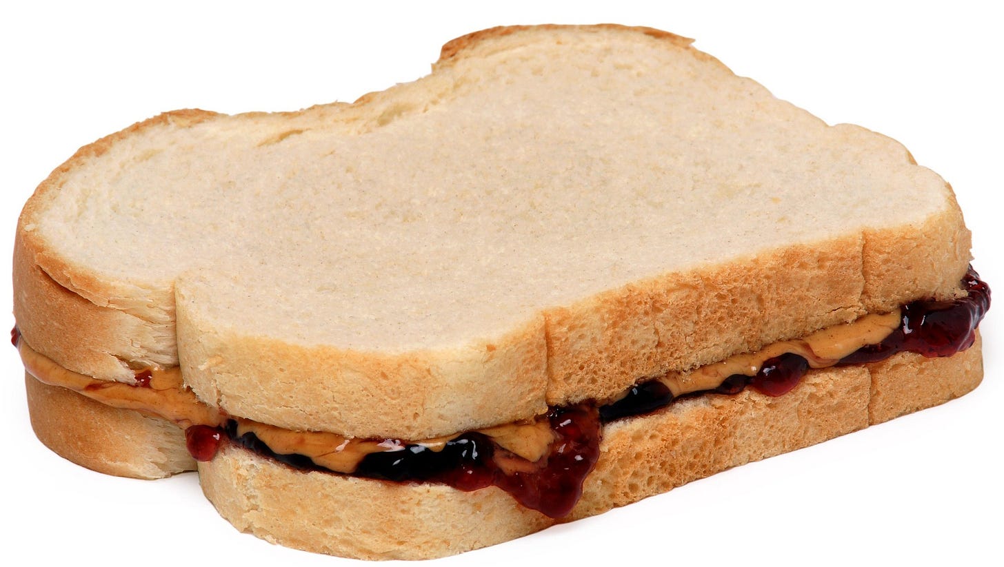 Peanut butter and jelly oozes out from between two slices of white bread