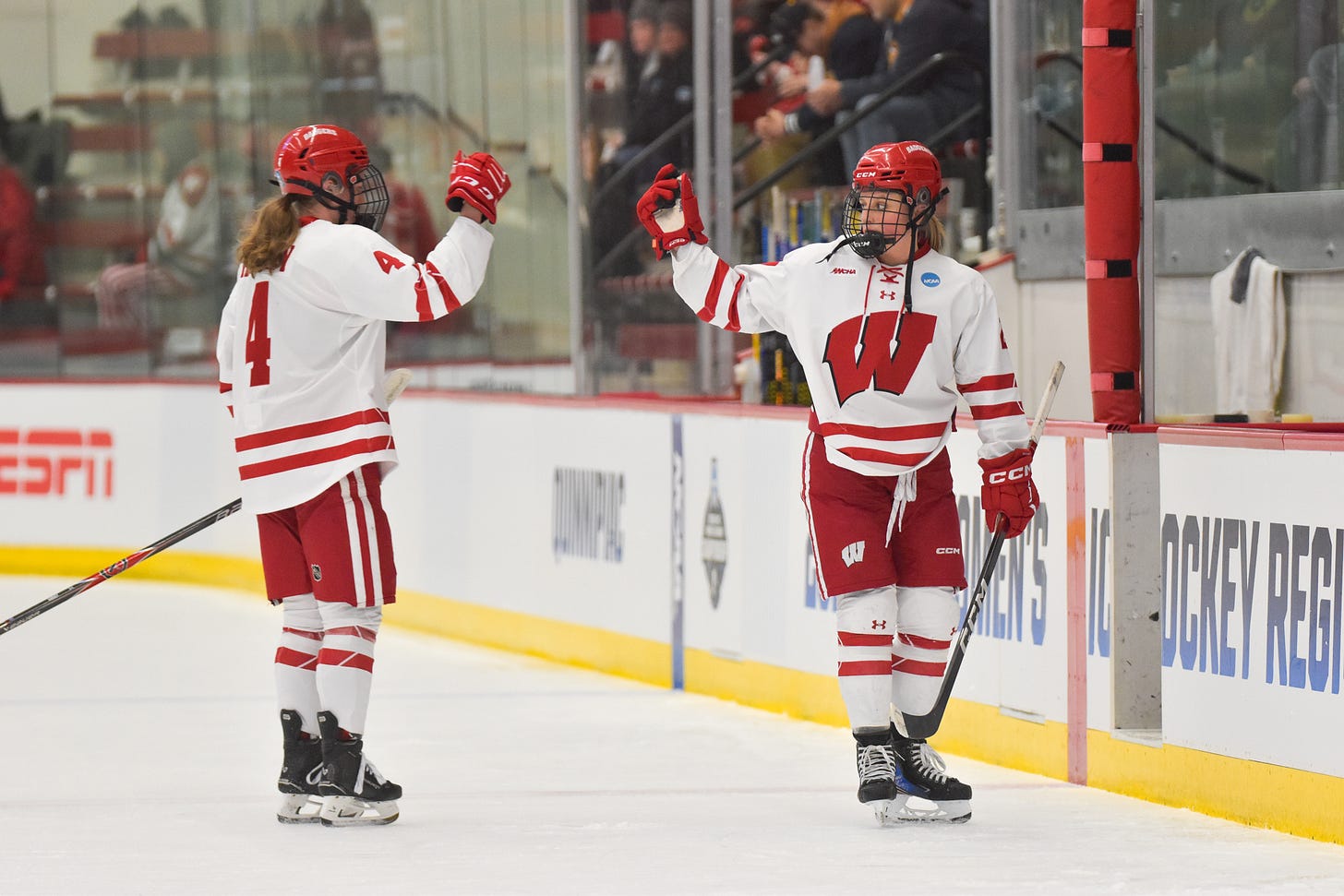 Wisconsin Badgers captain Carolien Harvey extends her right arm up to meet Kirsten Simms as the two leave the ice 