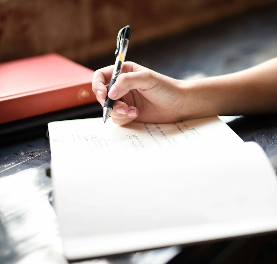 a person writing on a piece of paper with a pen