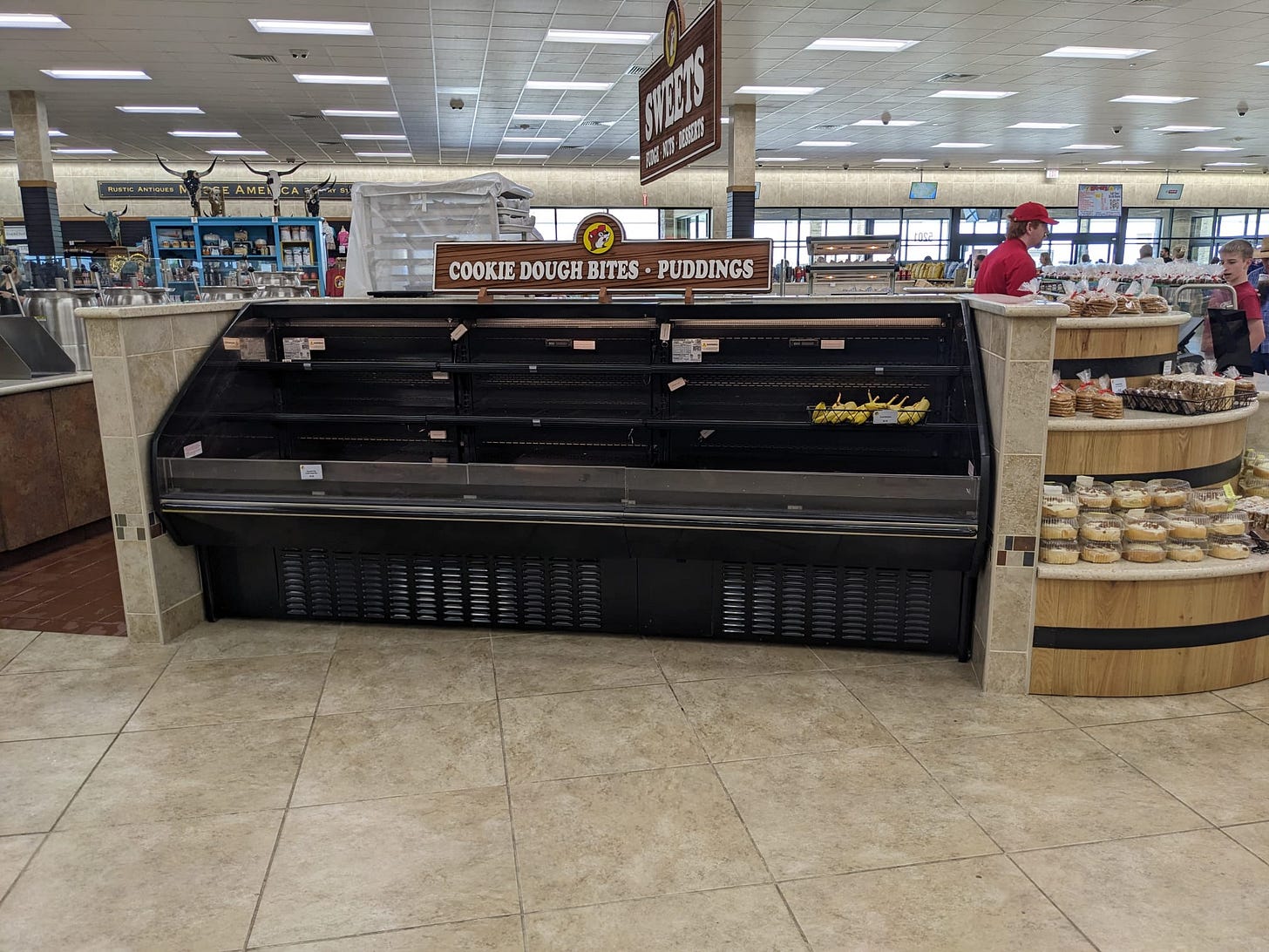 A photo of a shelf that says "cookie dough bites / puddings" but holds one case of bananas.