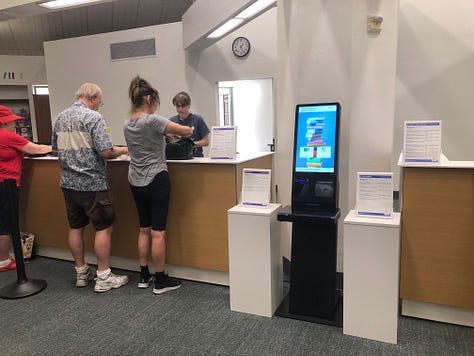 Adults and children in a public library borwworing, browsing, returning  books 