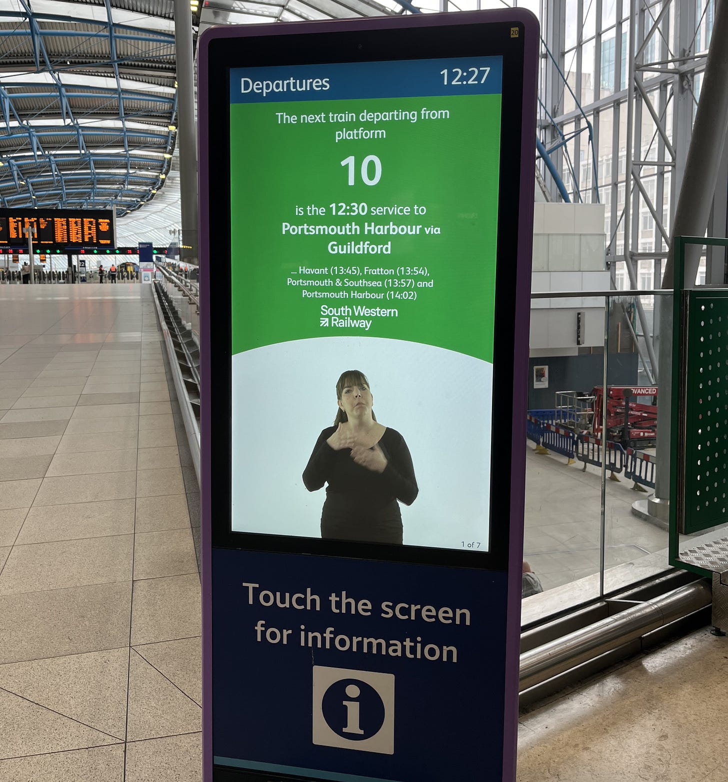 Photo of a screen showing train departure information and a video signer. Photo of a screen showing train departure information and a video signer.
