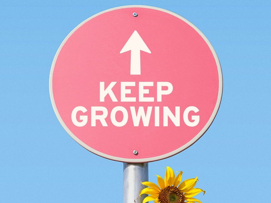 Pink sign with "keep growing" and sunflowers
