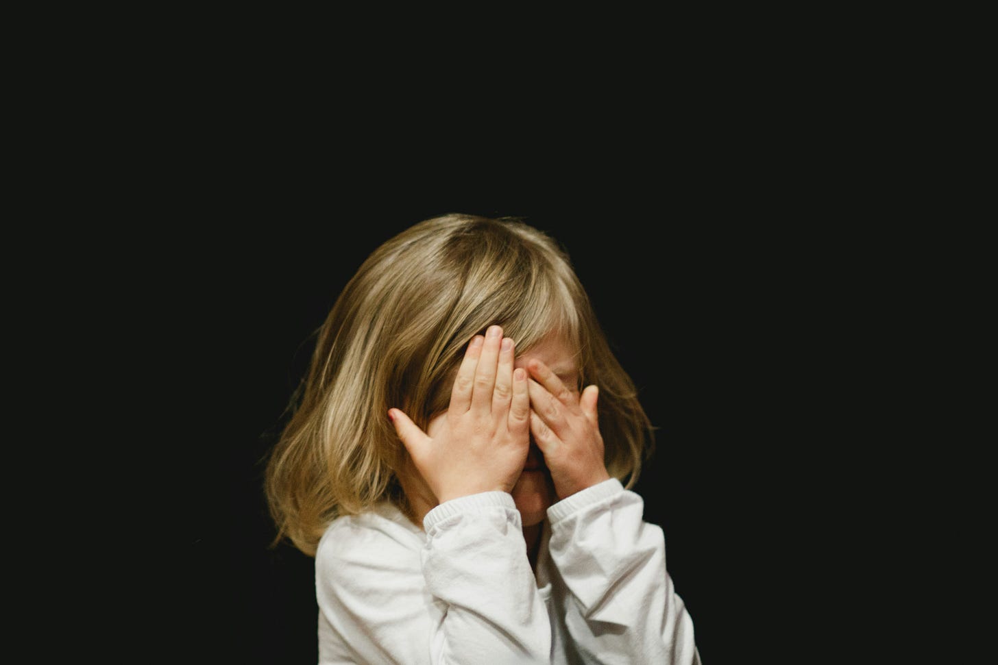 Little girl covering her eyes. Photo by Caleb Woods via Unsplash.