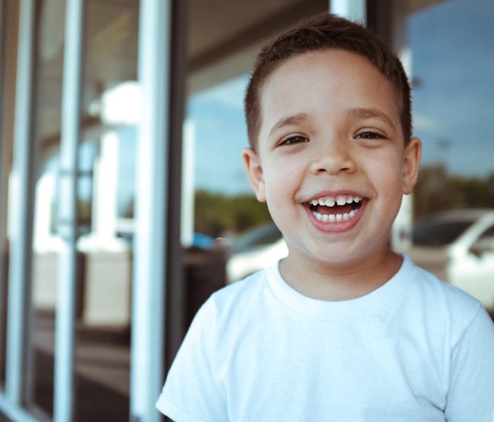 smiling boy wearing white crew-neck t-shirt during daytime