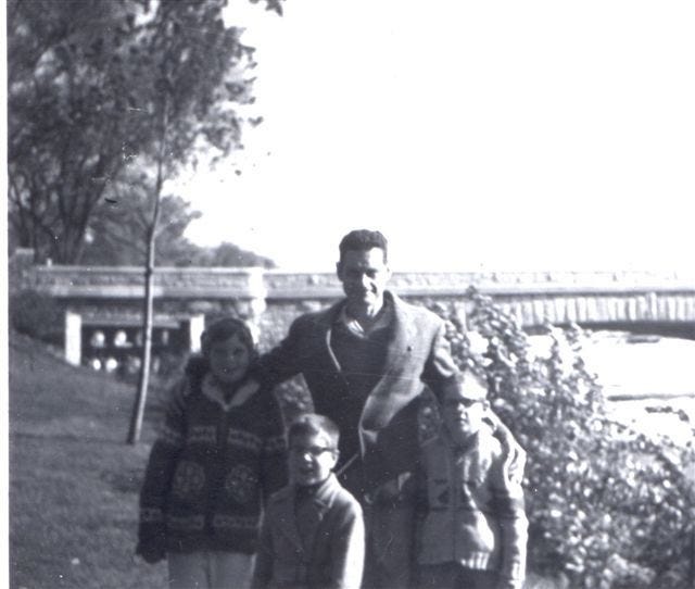 A person standing with his children

Description automatically generated