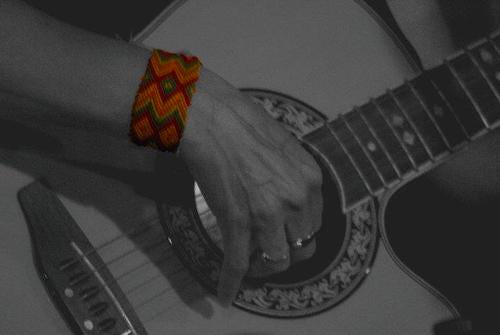woman playing guitar wearing red bracelet woman playing guitar wearing red bracelet