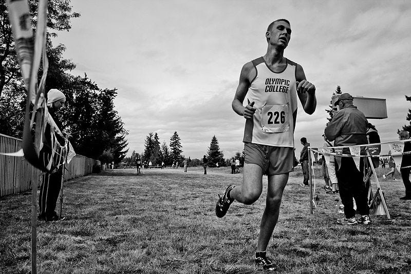 In black-and-white, a runner completes a marathon. He is exhausted.