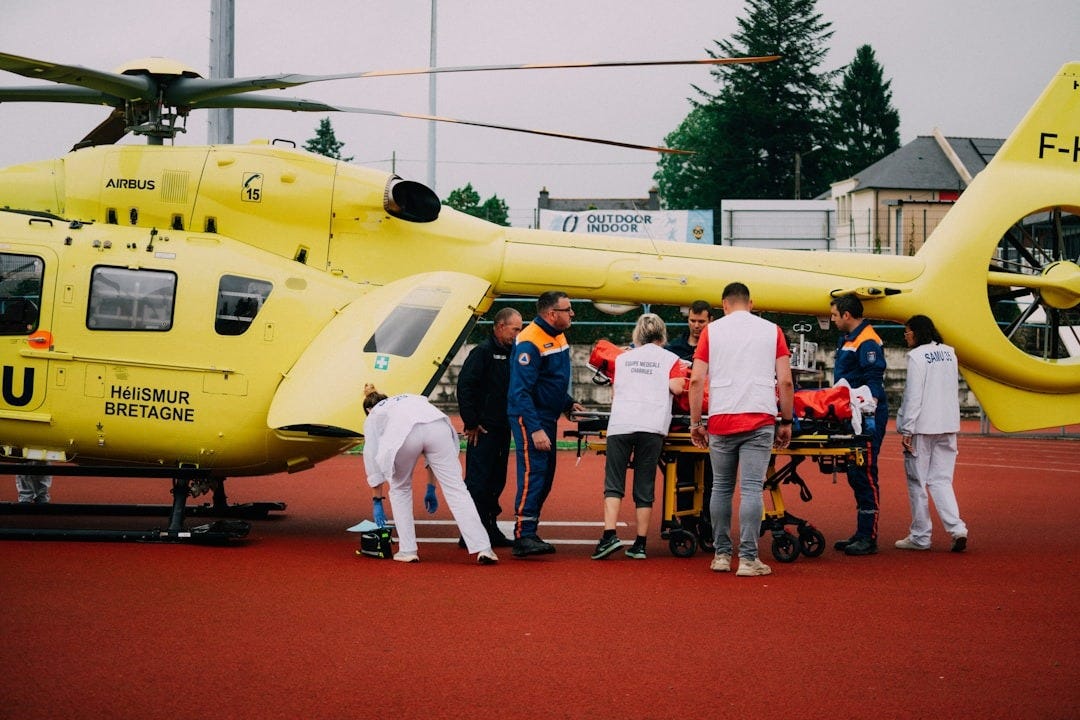 a group of people standing around a yellow helicopter a group of people standing around a yellow helicopter