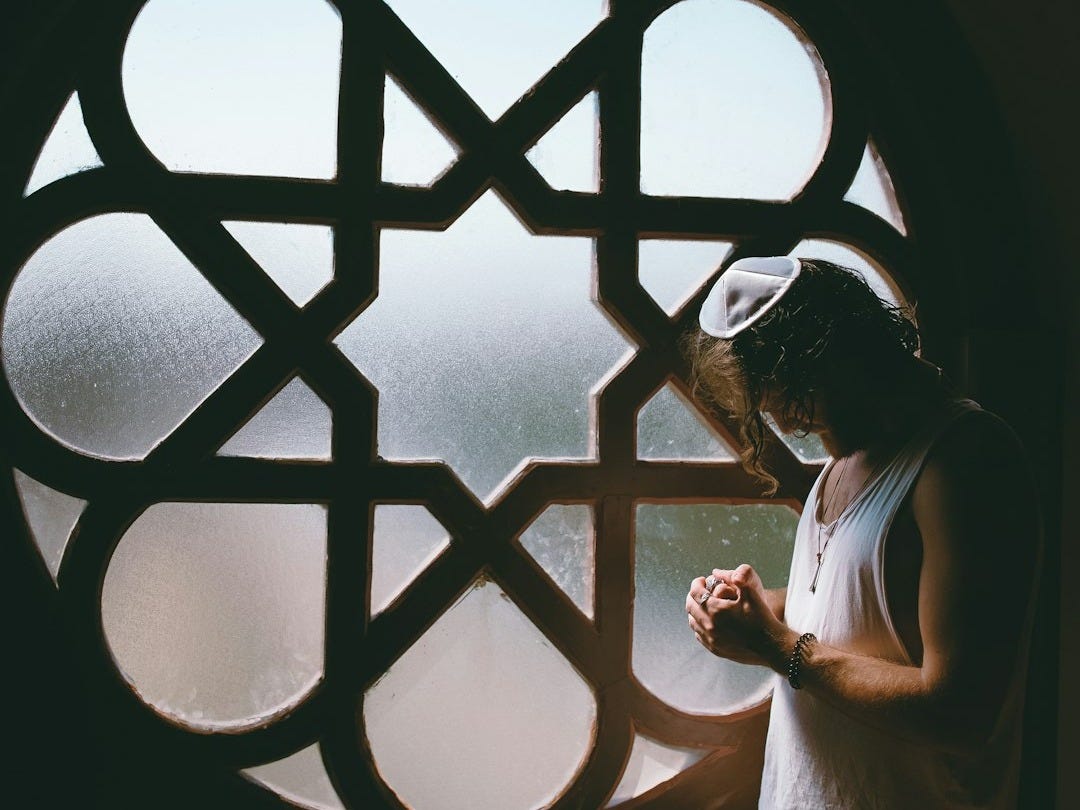man in white tank top beside glass window