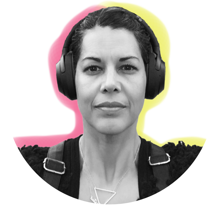 Autastic Founder Diane J. Wright, a biracial Afro-Caribbean, middle-aged woman with pulled-back dark hair wearing noise-cancelling headphones, a dark fuzzy sweater, and backpack straps. The photo is against a plain white background with a pink and yellow glow outline.