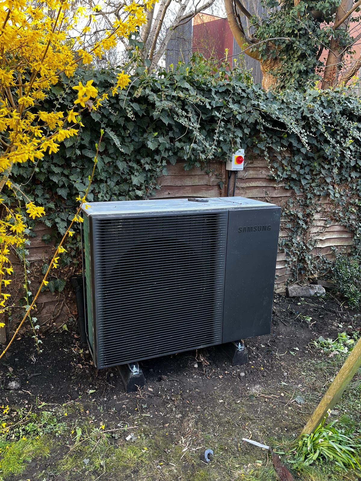 Photo of a large heat pump in front of a fence
