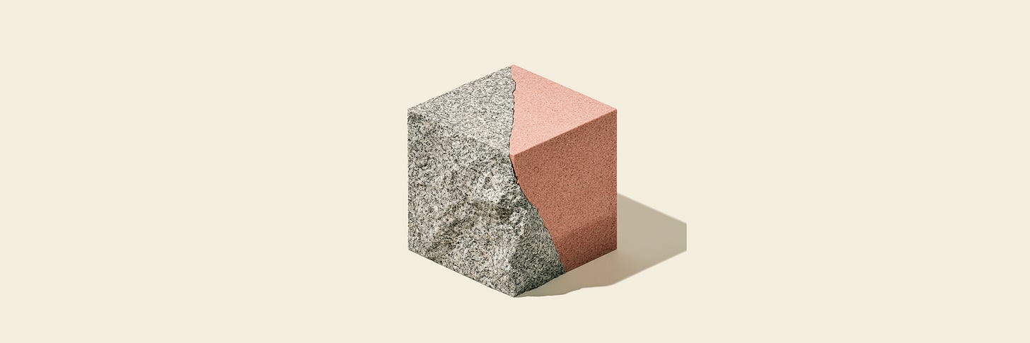 A cube split down the middle: rough, unpolished gray granite on one half, smooth polished rose-pink granite on the other, meeting at a jagged crack line, isometric style on a cream background.