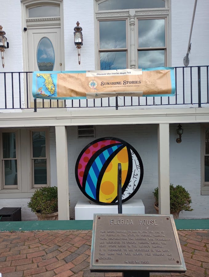 Grand Victorian building on left, and historical marker plus beachball mural on right