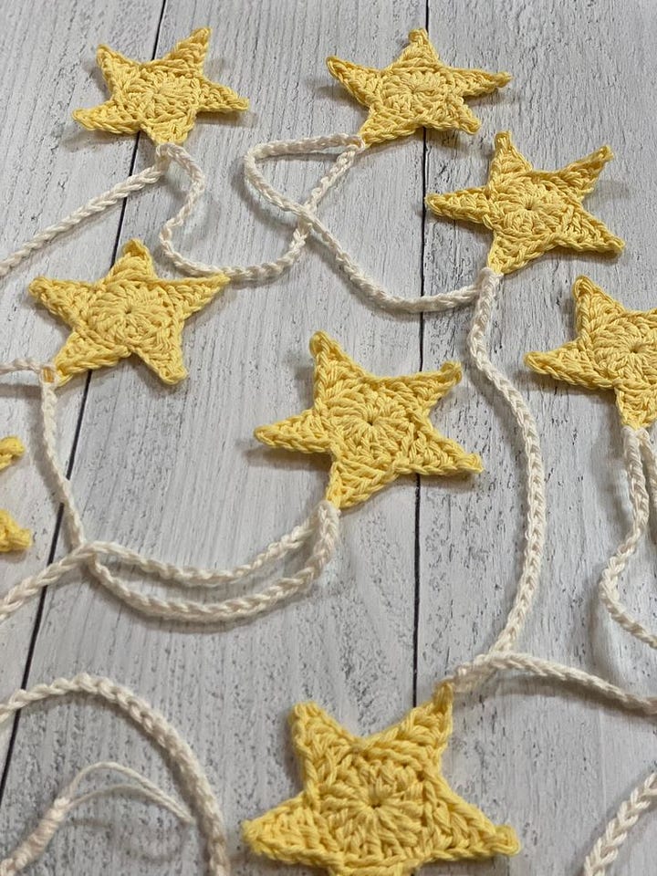 A crocheted garland strung with yellow stars and crochet mushrooms attached with a loop as an ornament