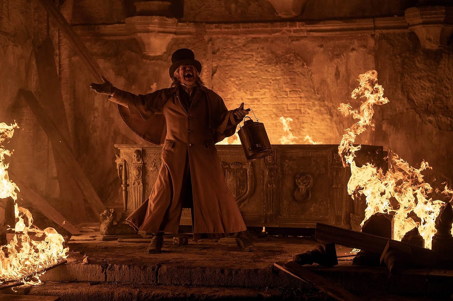 A still from the film. Willem Dafoe laughs maniacally in front of a burning coffin.
