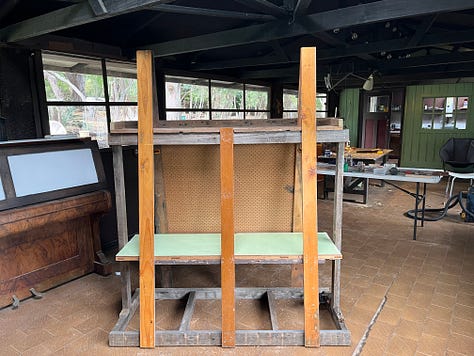 A wooden frame for storing and painitng wooden panels and tools and a series of coffee can lanterns in the process of being restored.