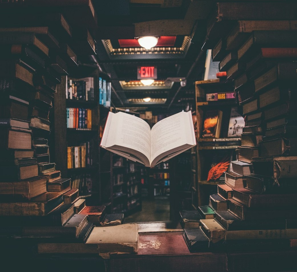 view of floating open book from stacked books in library
